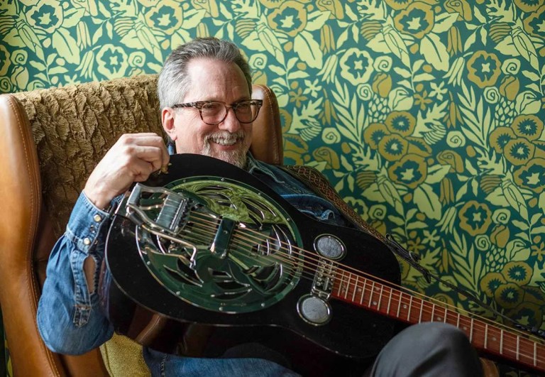 Jerry Douglas smiles while holding a Dobro. Photo by Scott Simontacchi