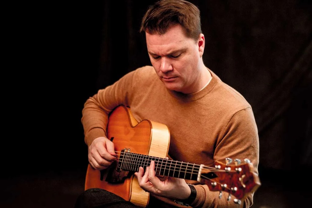 Sean-McGowan-playing-an-acoustic-guitar-photo-Joey-Lusterman