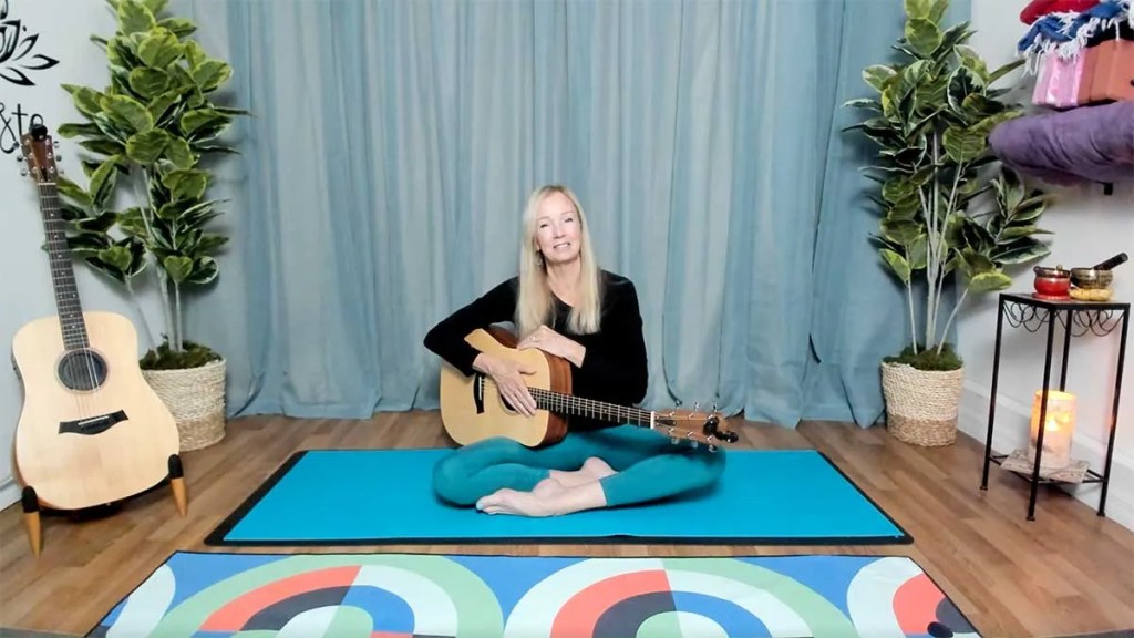 Female acoustic guitarist in yoga studio with guitar